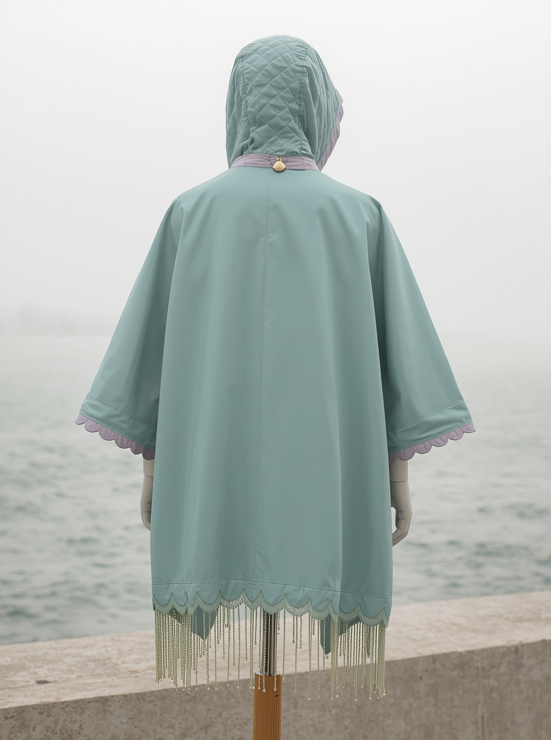 DEEP SEA poncho from the back: quilted hood with shell-lilac lining, scalloped trim and beaded hem
