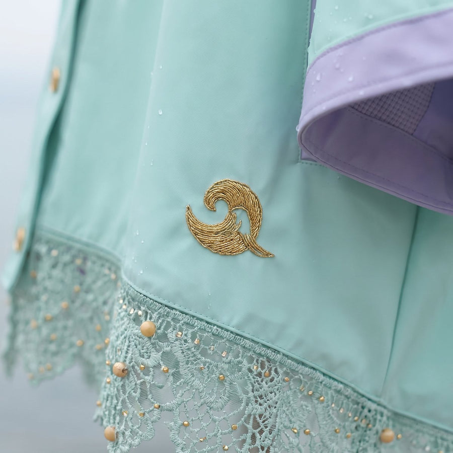 Close-up of the DEEP SEA hem with a small gold embroidered wave curl above the beaded lace