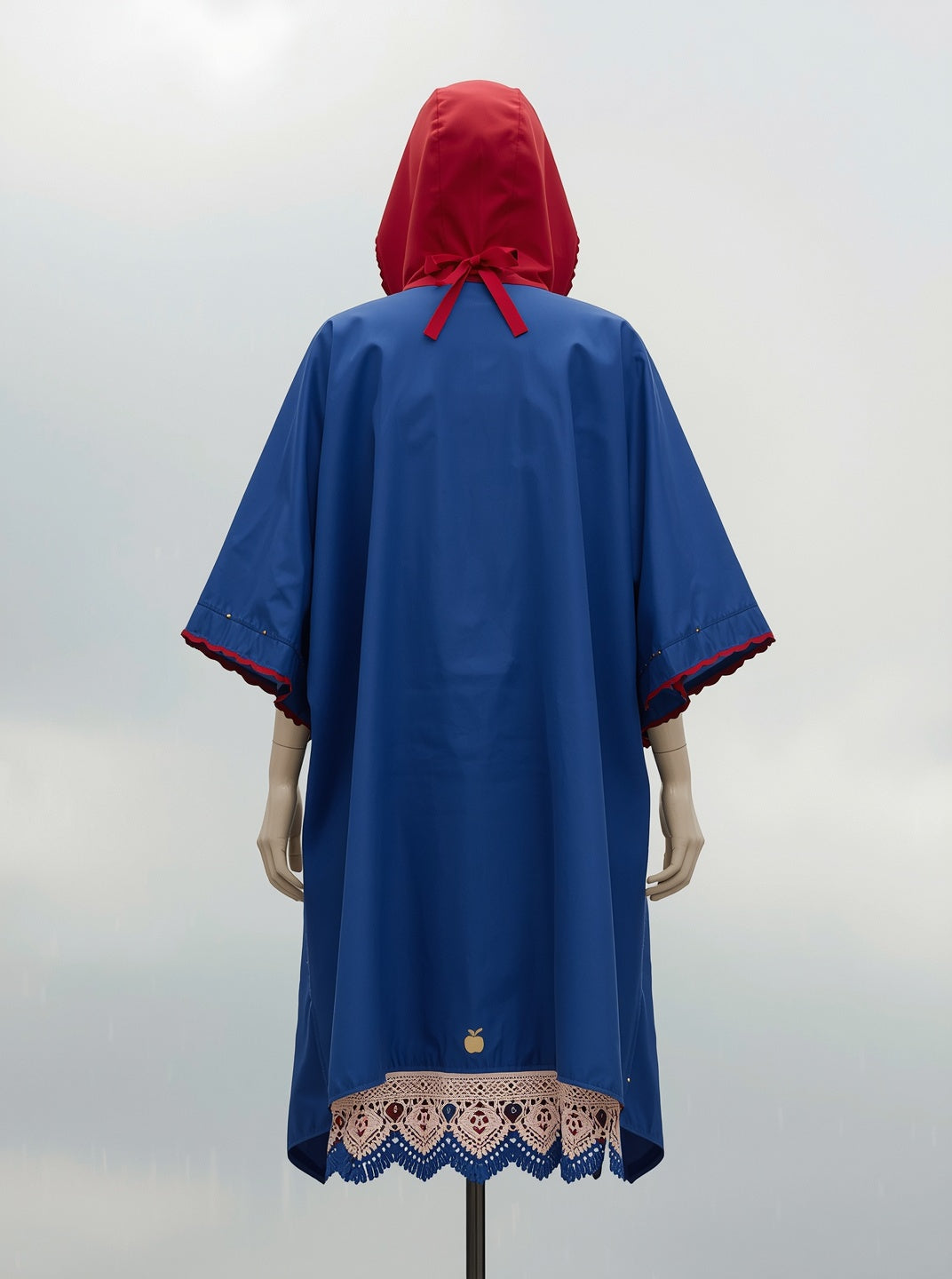FAIREST poncho from the back: apple-red hood with a ribbon bow, storybook blue cape and lace hem