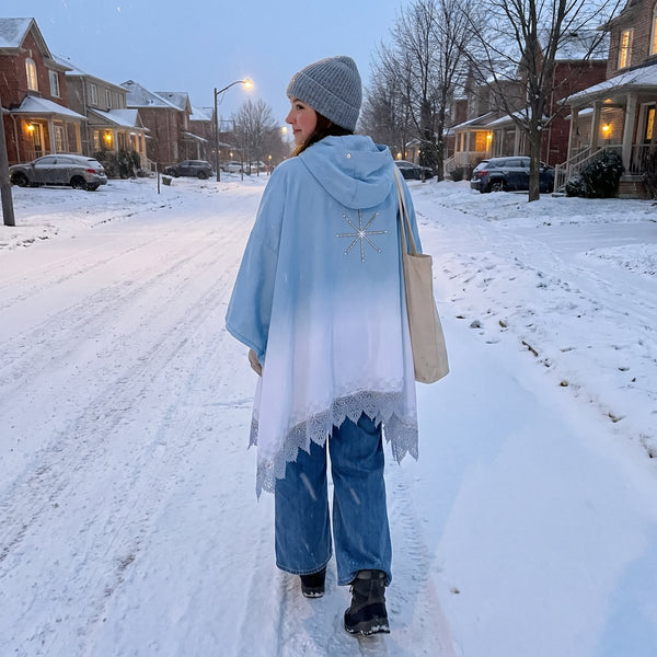 FROST poncho seen from behind on a snowy street, worn with jeans, a beanie and a tote